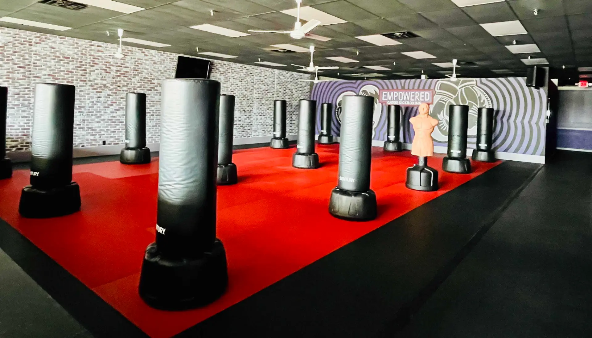 Kickboxing class floor lined with freestanding heavy bags on red and black mats at EMPOWERED Fitness Studio in Evansville, IN